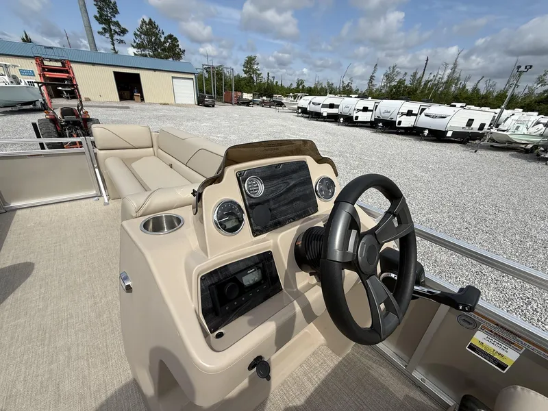 Slide: The Image of 2025 Avalon Venture 21 CRUISE boat interior with steering wheel and seating, parked near RVs. - 7