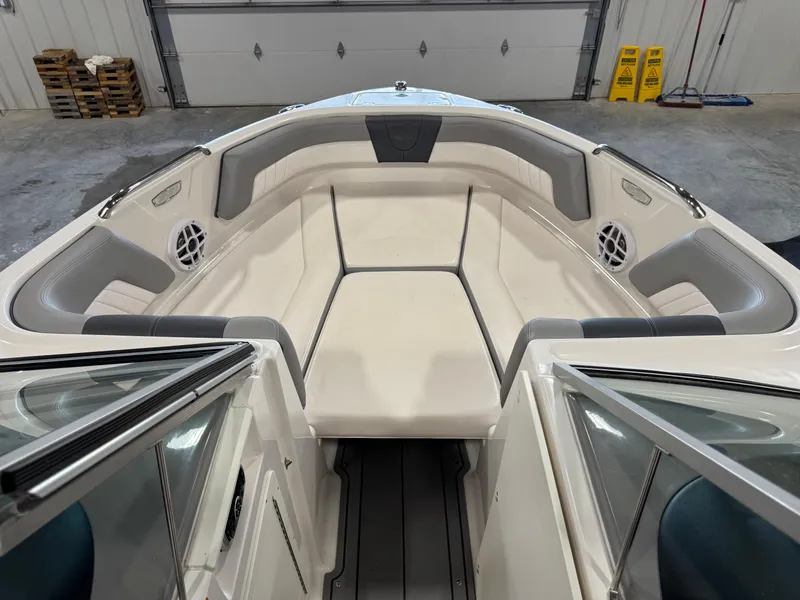 Slide: The Image of 2021 Chaparral 21 SSi boat interior with cushioned seating and speakers in a garage. - 14