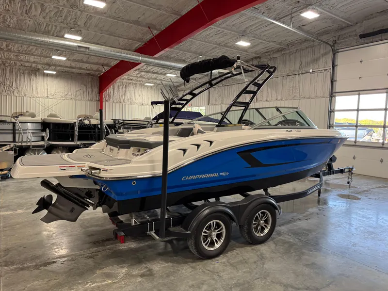 Slide: The Image of 2021 Chaparral 21 SSi boat in a showroom, featuring a sleek blue and white design. - 3