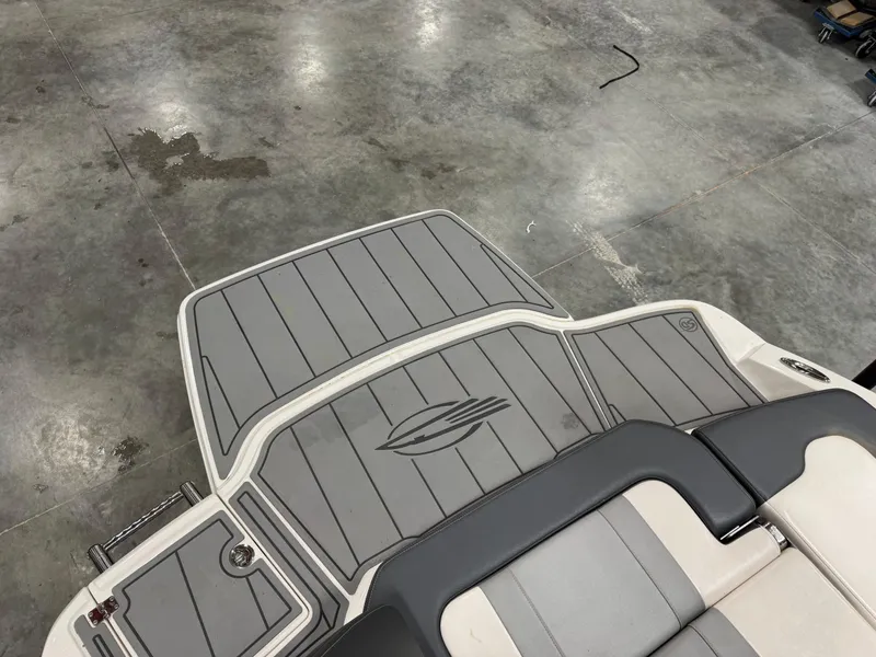 Slide: The Image of 2021 Chaparral 21 SSi boat deck with gray and white seating, in a garage setting. - 9