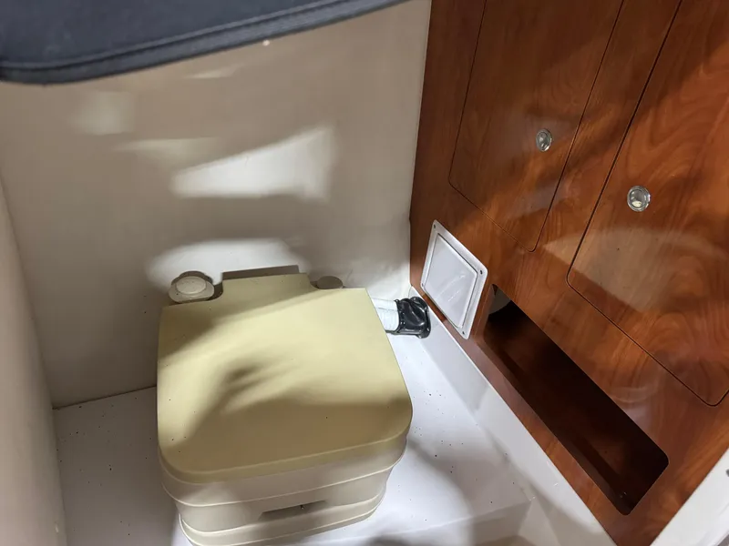 Slide: The Image of 2008 Four Winns SL 262 boat interior with portable toilet and wooden cabinet. - 9