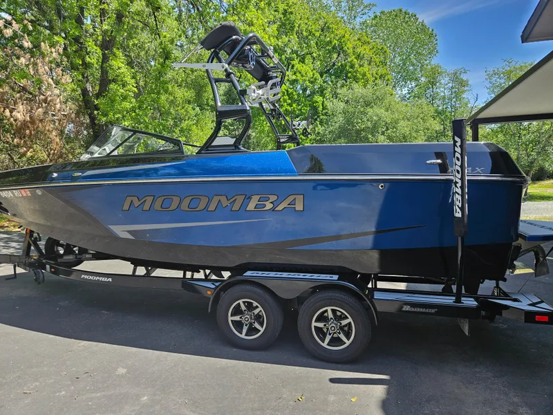 Slide: The Image of 2020 Moomba Max boat on trailer, blue and black, parked outdoors. - 27