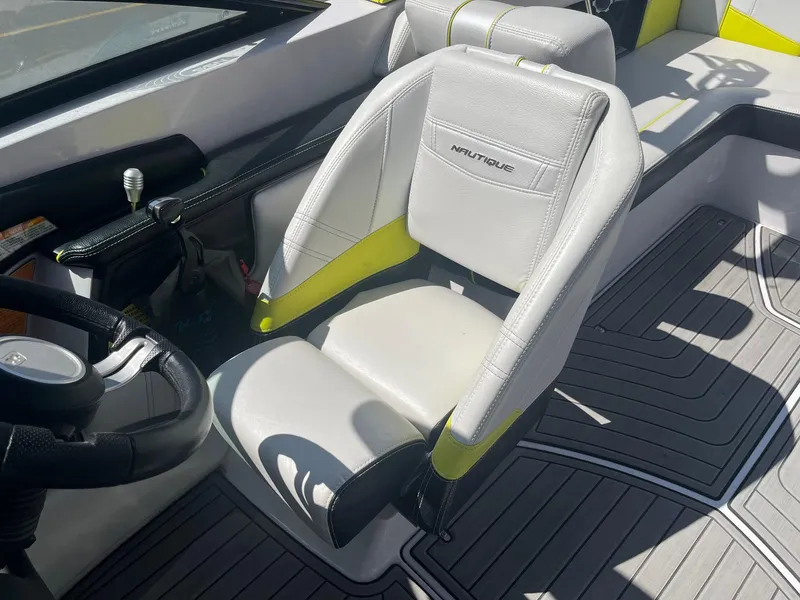 Slide: The Image of 2014 Nautique 230 TEAM EDITION boat interior with steering wheel and branded seat. - 26