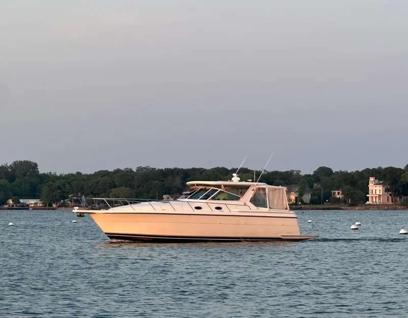 Slide: The Image of 1998 Tiara Yachts 4000 Express cruising on a calm lake with scenic shoreline. - 0