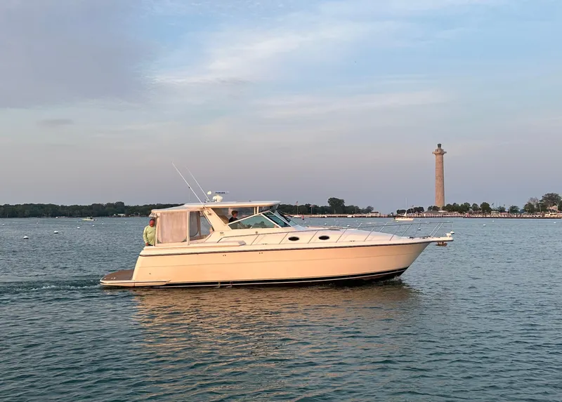 Slide: The Image of 1998 Tiara Yachts 4000 Express cruising near a coastal monument at sunset. - 1