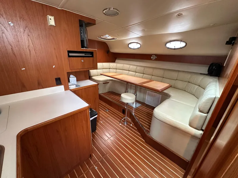 Slide: The Image of 1998 Tiara Yachts 4000 Express interior with wood paneling, white seating, and dining table. - 10