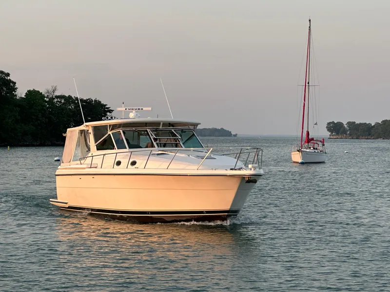 Slide: The Image of 1998 Tiara Yachts 4000 Express cruising on a serene lake with a sailboat nearby. - 2