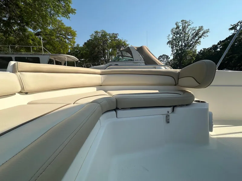 Slide: The Image of 2021 NauticStar 211 Hybrid boat interior with beige seating under clear blue sky. - 11