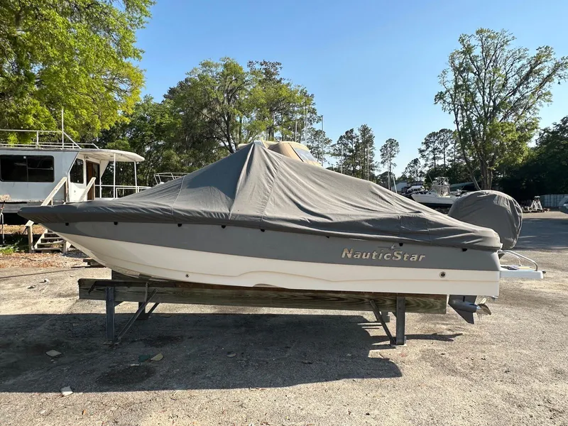 Slide: The Image of 2021 NauticStar 211 Hybrid boat covered, parked outdoors on a sunny day. - 33