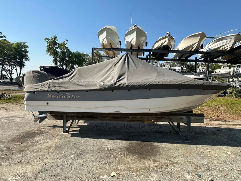 Slide: The Image of 2021 NauticStar 211 Hybrid boat covered and stored outdoors on a sunny day. - 34