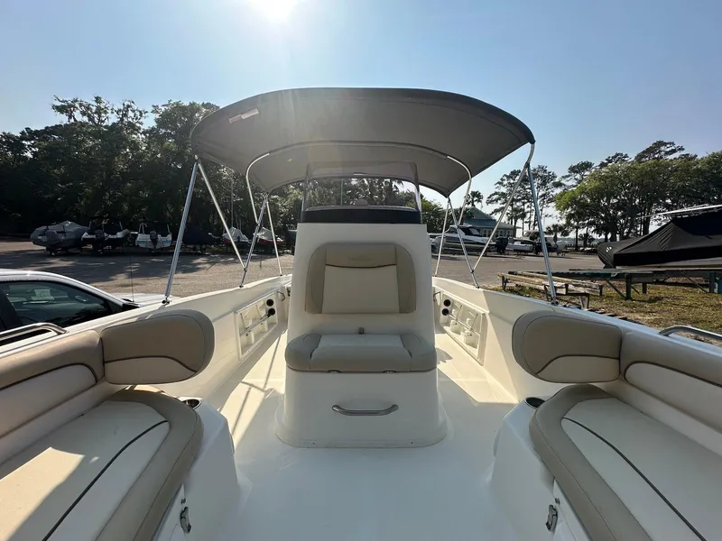 Slide: The Image of 2021 NauticStar 211 Hybrid boat interior with seating and canopy, parked outdoors. - 9