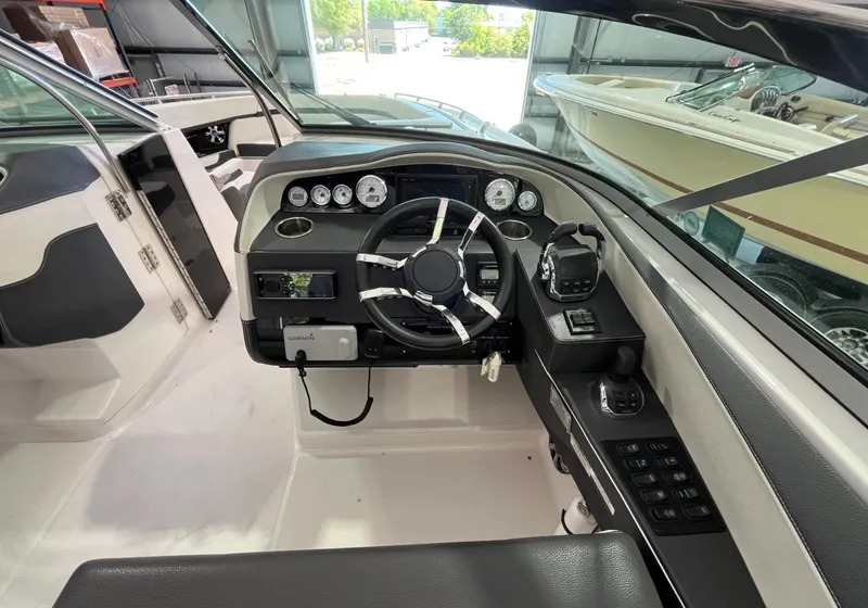 Slide: The Image of 2016 Regal 3200 Bowrider cockpit with steering wheel and control panel in a boat garage. - 7