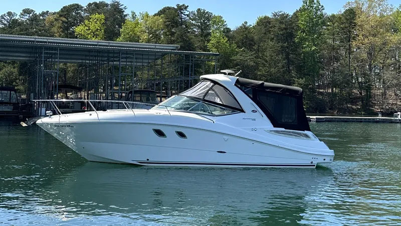 Slide: The Image of 2014 Sea Ray 330 Sundancer boat on calm water near a marina. - 1