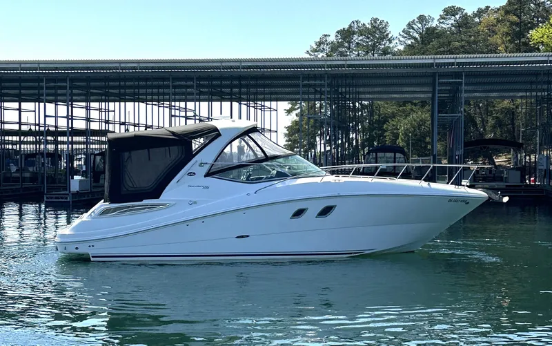 Slide: The Image of 2014 Sea Ray 330 Sundancer boat docked on calm water near a marina. - 2