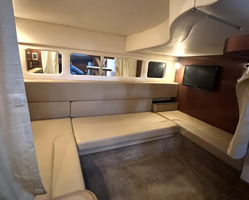 Slide: The Image of 2014 Sea Ray 330 Sundancer cabin interior with beige seating and wall-mounted TV. - 25