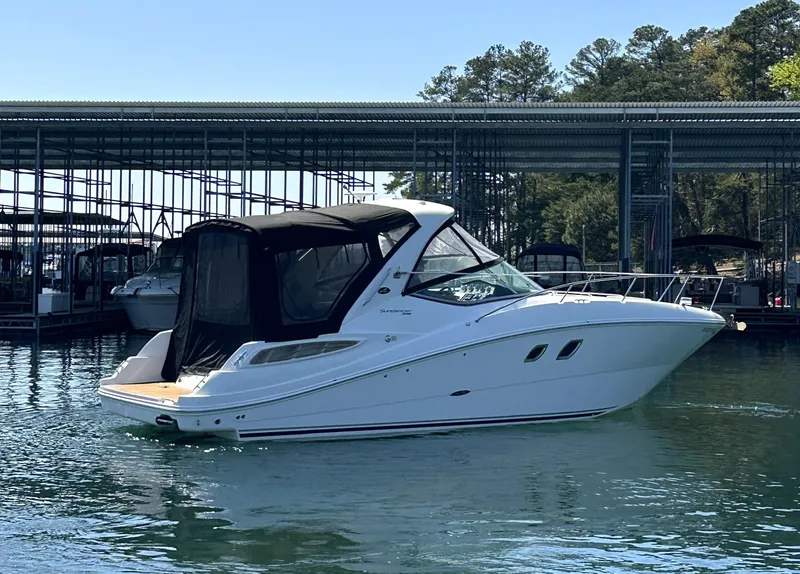 Slide: The Image of 2014 Sea Ray 330 Sundancer boat docked on calm water, surrounded by marina. - 8