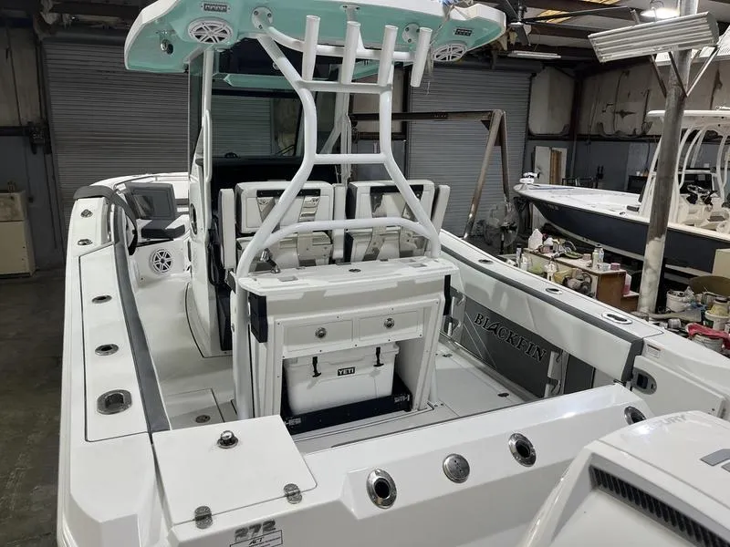 Slide: The Image of 2019 Blackfin 272 CC boat interior with seating and storage in a warehouse setting. - 6