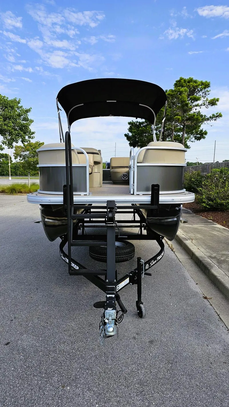 Slide: The Image of 2025 Sun Tracker Party Barge 18 DLX pontoon boat on trailer, parked outdoors. - 5