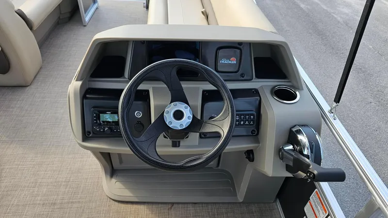 Slide: The Image of 2025 Sun Tracker Party Barge 18 DLX steering console with controls and cup holder. - 7