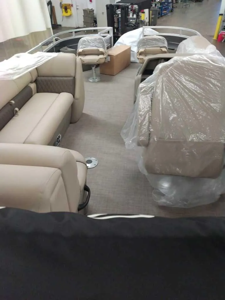 Slide: The Image of 2025 Sun Tracker Fishin' Barge 20 DLX interior with beige seating and protective covers. - 2