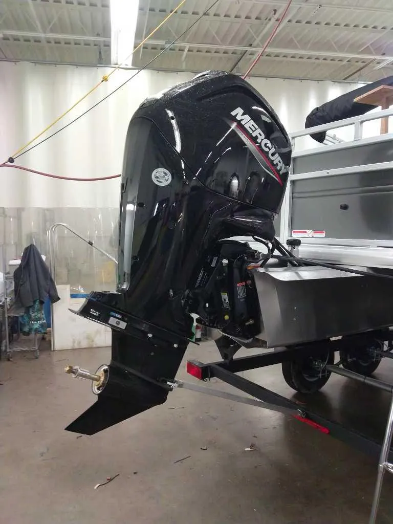 Slide: The Image of 2025 Sun Tracker Fishin' Barge 20 DLX with Mercury outboard motor in a workshop. - 3