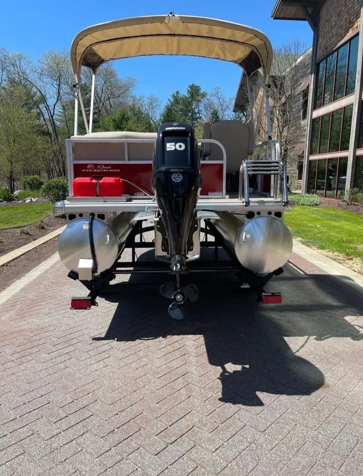 Slide: The Image of 2025 Sun Tracker Bass Buggy 16 XL Select pontoon boat with 50 HP engine, parked outdoors. - 7