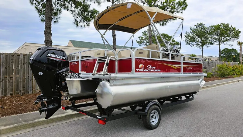 Slide: The Image of 2025 Sun Tracker Bass Buggy 18 DLX pontoon boat with Mercury outboard motor on trailer. - 3