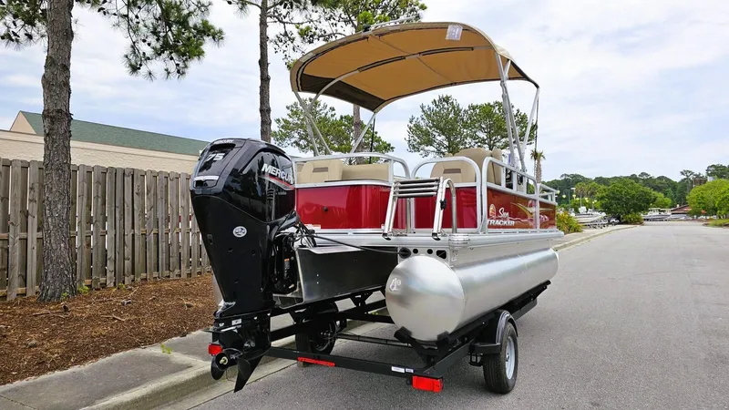 Slide: The Image of 2025 Sun Tracker Bass Buggy 18 DLX pontoon boat on trailer, parked on a street. - 4