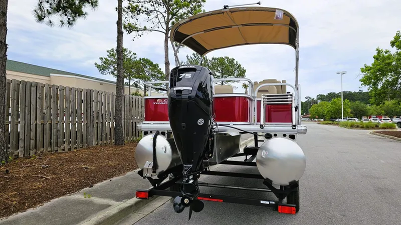 Slide: The Image of 2025 Sun Tracker Bass Buggy 18 DLX pontoon boat with outboard motor, parked on a street. - 5