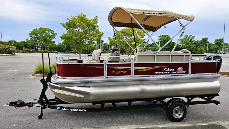 Slide: The Image of 2025 Sun Tracker Bass Buggy 18 DLX pontoon boat on trailer in parking lot. - 8