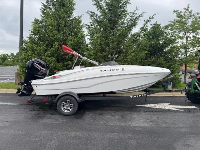 The Image of 2025 Tahoe T16 boat on trailer, parked outdoors, with trees in the background. - 0