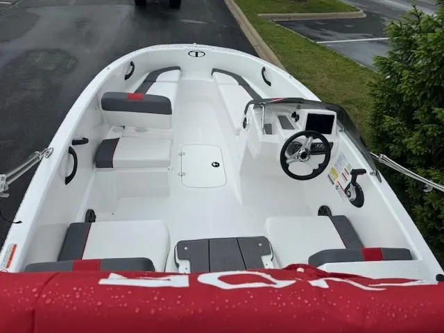 Slide: The Image of 2025 Tahoe T16 boat interior with seating, steering wheel, and console, parked on wet pavement. - 3
