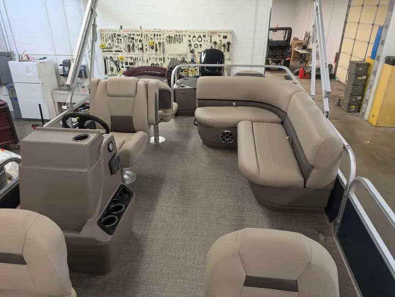 Slide: The Image of 2025 Sun Tracker Bass Buggy 18 DLX pontoon boat interior with beige seating and steering console. - 3