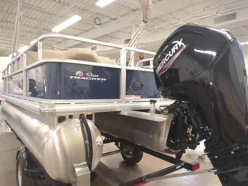 Slide: The Image of 2025 Sun Tracker Bass Buggy 18 DLX pontoon boat with Mercury outboard motor in a showroom. - 4