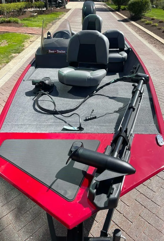 Slide: The Image of 2025 Tracker Bass Tracker Classic XL boat with red exterior and gray seating on a paved path. - 3