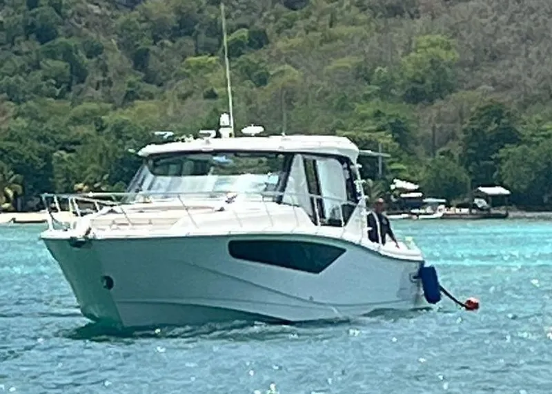 The Image of Boston Whaler 405 Conquest 2021 cruising on clear turquoise water near lush green shoreline. - 0