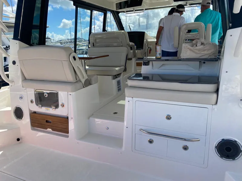 Slide: The Image of 2021 Boston Whaler 405 Conquest interior with seating and storage, docked under a clear sky. - 7