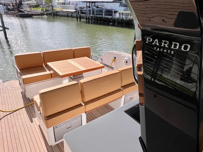 Slide: The Image of 2024 Pardo Yachts P38 with elegant seating and table on deck, docked by the water. - 30