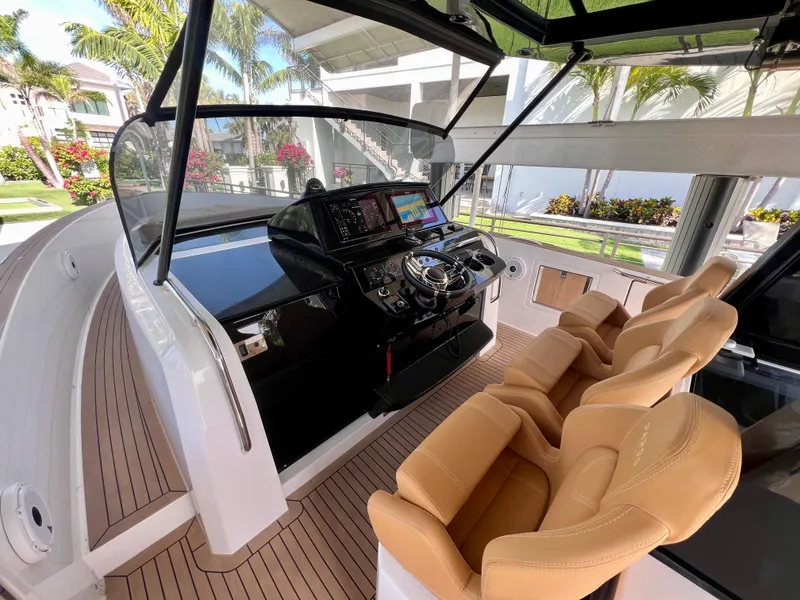 Slide: The Image of 2024 Pardo Yachts P38 helm with modern controls and tan seating, docked in a tropical setting. - 4