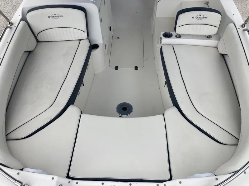 Slide: The Image of 2020 Stingray 212 boat interior with white cushioned seating and cup holders. - 11