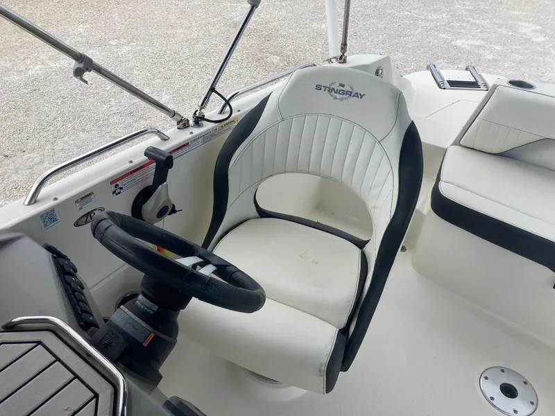 Slide: The Image of 2020 Stingray 212 boat interior with steering wheel and cushioned seating. - 14