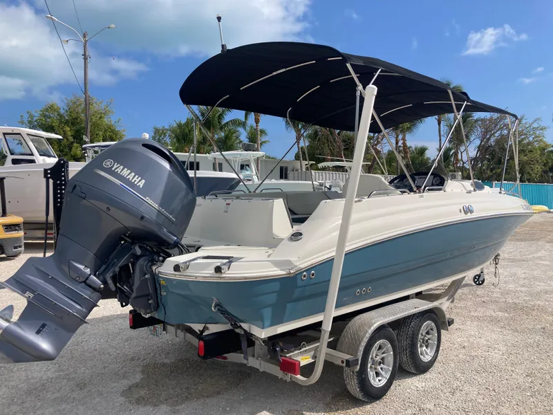 Slide: The Image of 2020 Stingray 212 boat with Yamaha outboard motor on a trailer, parked outdoors. - 3