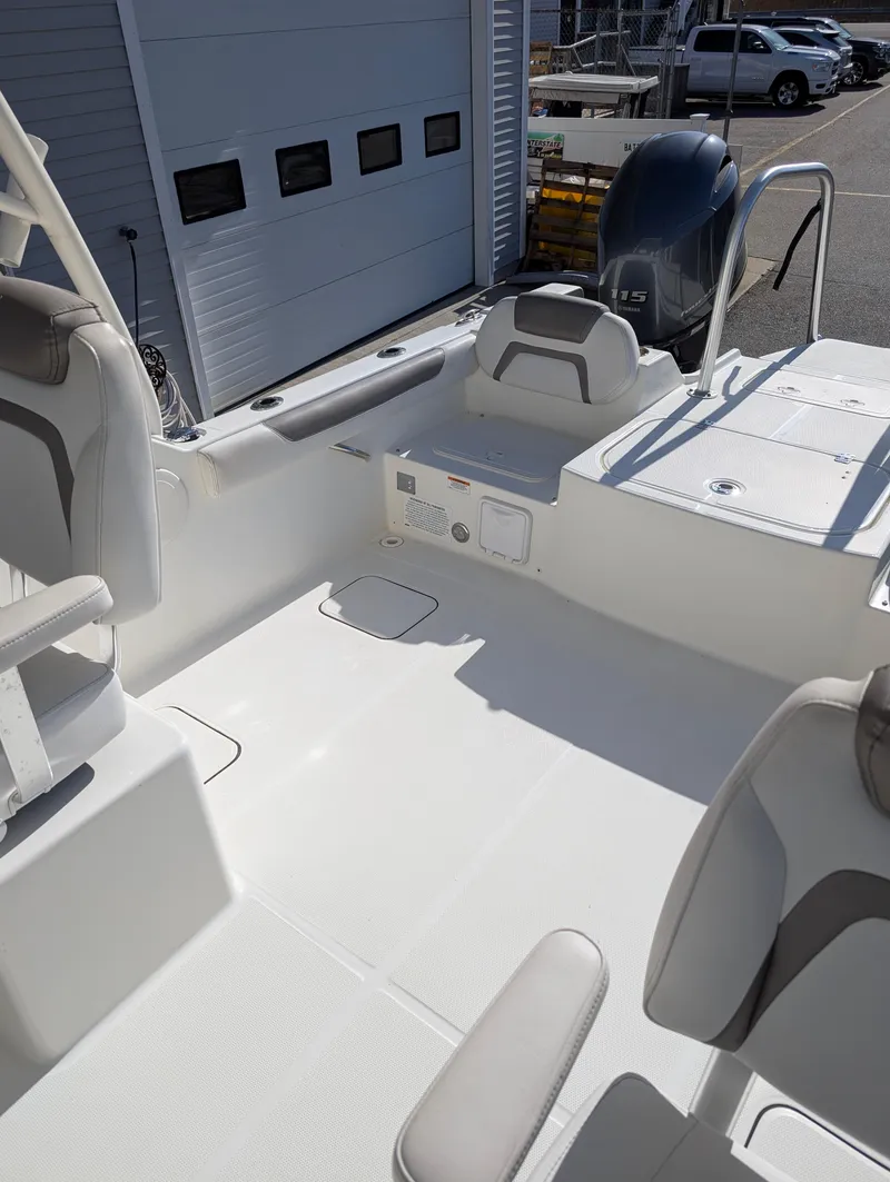 Slide: The Image of 2018 World Cat 230DC boat interior with seating and storage, docked near a building. - 10
