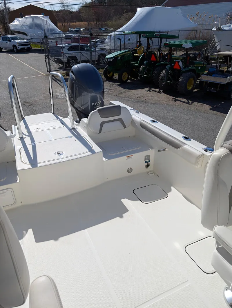 Slide: The Image of 2018 World Cat 230DC boat interior with seating and outboard motor in a marina setting. - 11