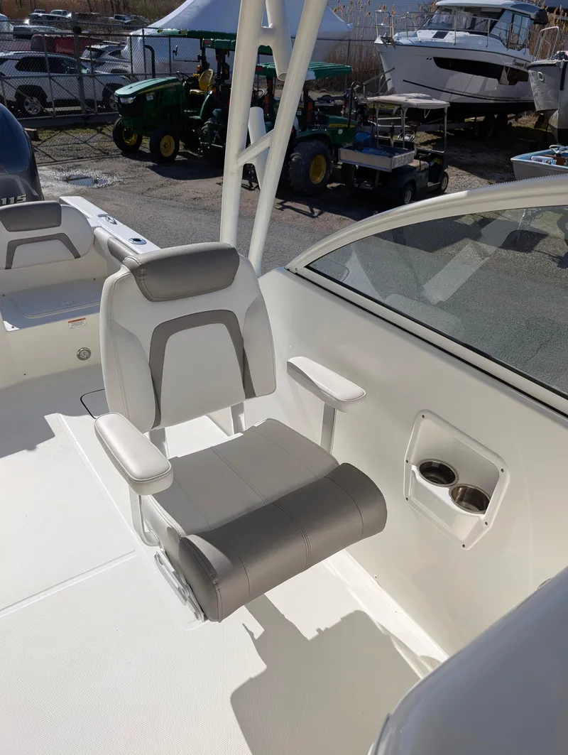 Slide: The Image of 2018 World Cat 230DC boat interior with gray and white seating, cup holders, and outdoor setting. - 15