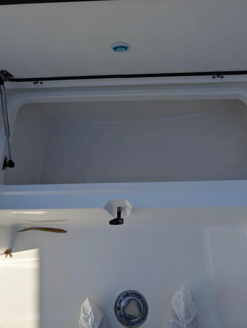 Slide: The Image of 2018 World Cat 230DC boat storage compartment with open lid and latch mechanism. - 18
