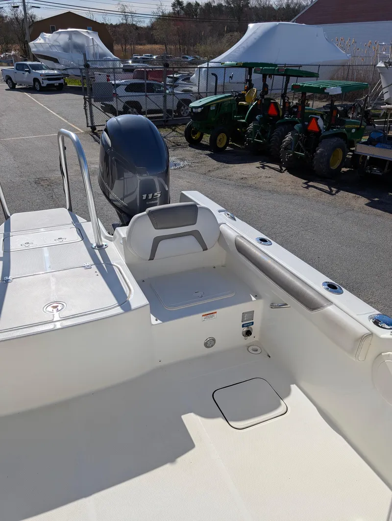 Slide: The Image of 2018 World Cat 230DC boat interior with engine, parked near tractors and tents. - 21