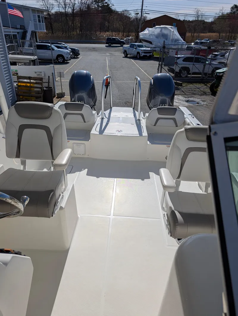 Slide: The Image of 2018 World Cat 230DC boat interior with seating and dual engines in a marina setting. - 9