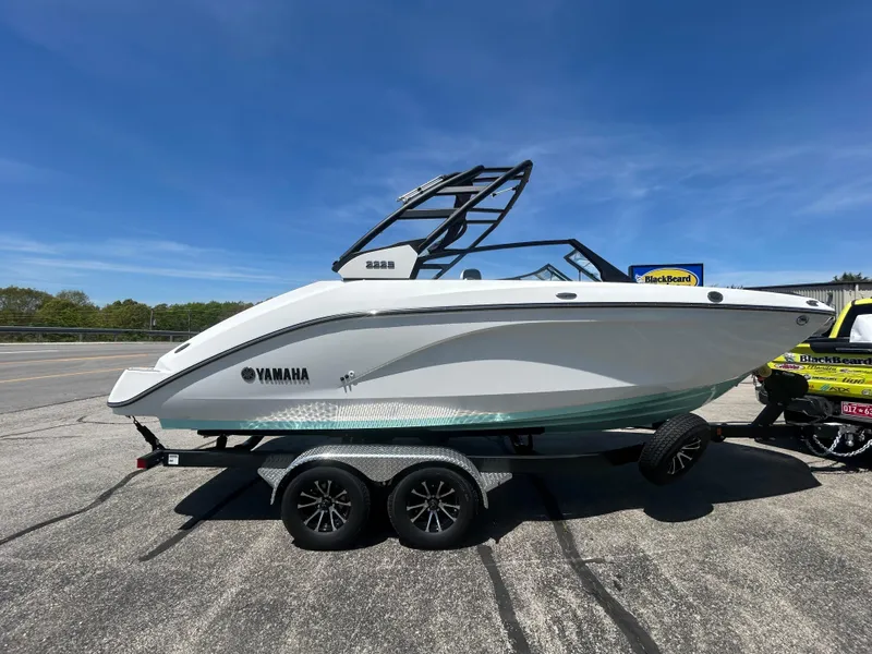 Slide: The Image of 2025 Yamaha Boats 222S on trailer, sleek design, parked outdoors under clear blue sky. - 3
