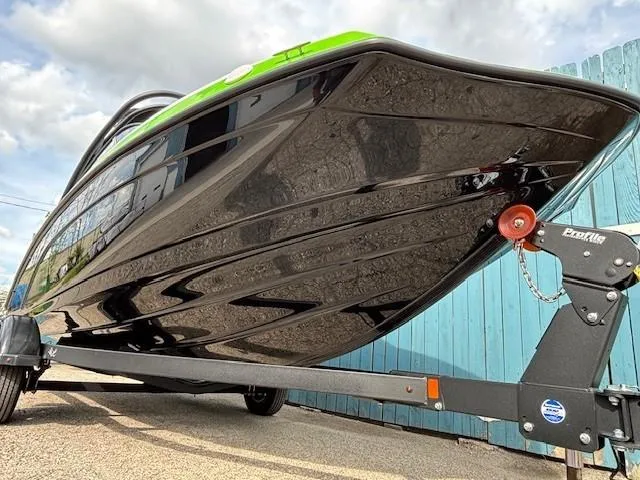 Slide: The Image of 2022 Yamaha AR190 boat on trailer, sleek black hull, vibrant green accents, parked outdoors. - 2